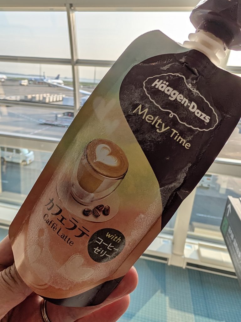 羽田空港で買ったハーゲンダッツの「メルティタイム カフェラテ」。窓の外に駐機中の飛行機が見える