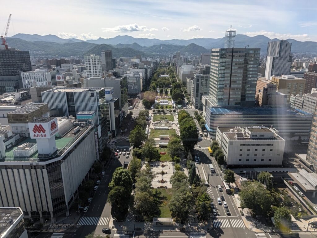 テレビ塔の展望台から見下ろした大通公園と札幌の街並み。遠くに山並みが見える