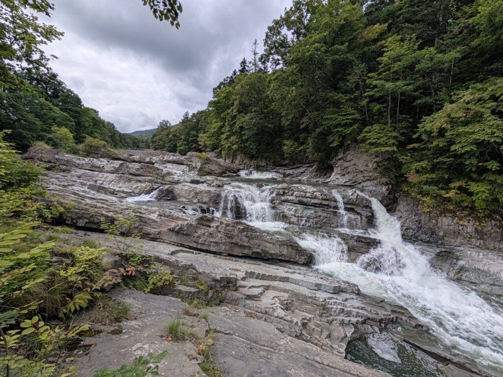 芦別の三段滝。岩肌を幾筋にも分かれて流れ落ちる水と、周囲の緑