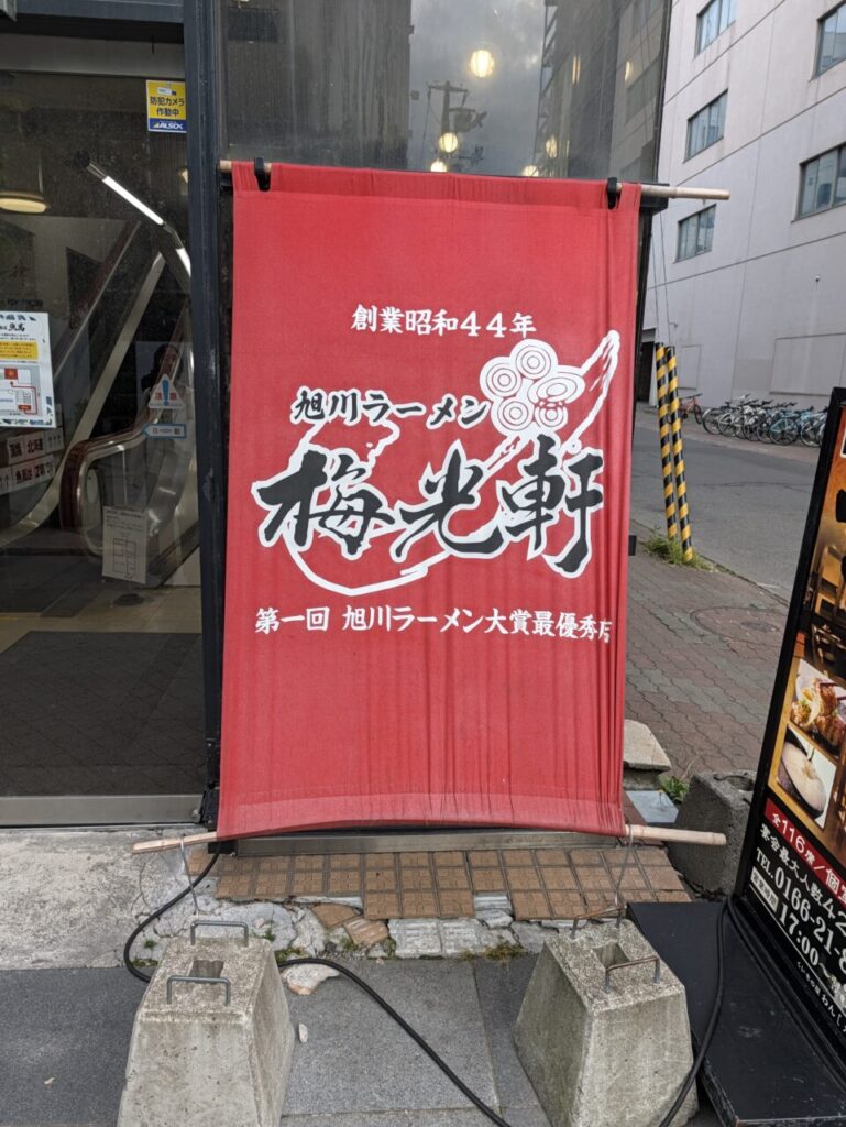 梅光軒 旭川本店の赤い暖簾。「創業昭和44年」「旭川ラーメン」の文字が入っている