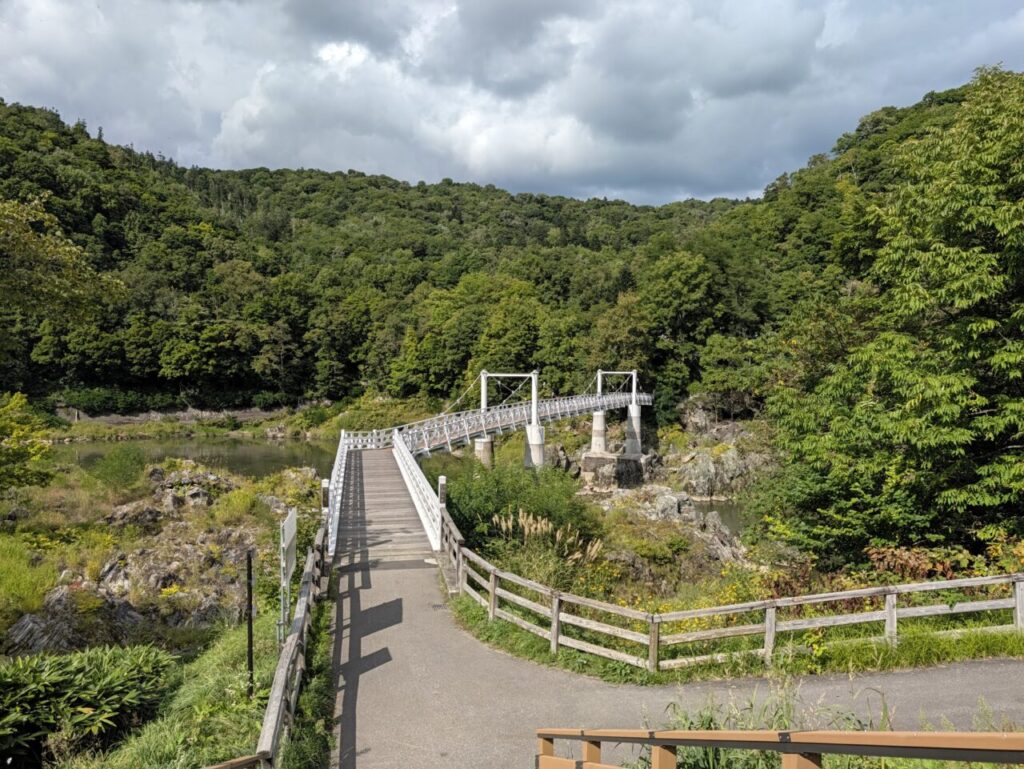 神居古潭の吊り橋。石狩川を渡る白い吊橋と、緑の山